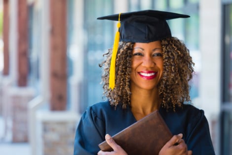 a woman holding her diploma to her chest smiling happy