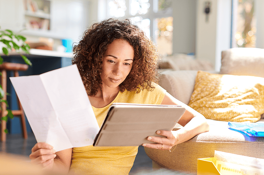 Woman reading a tablet and holding a piece of paper