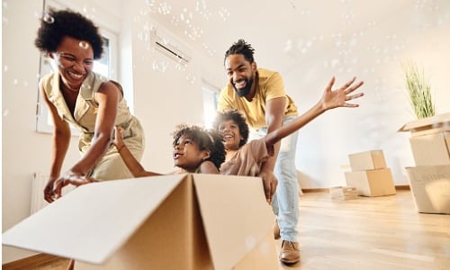 Parents having fun while pushing their kids in cardboard box