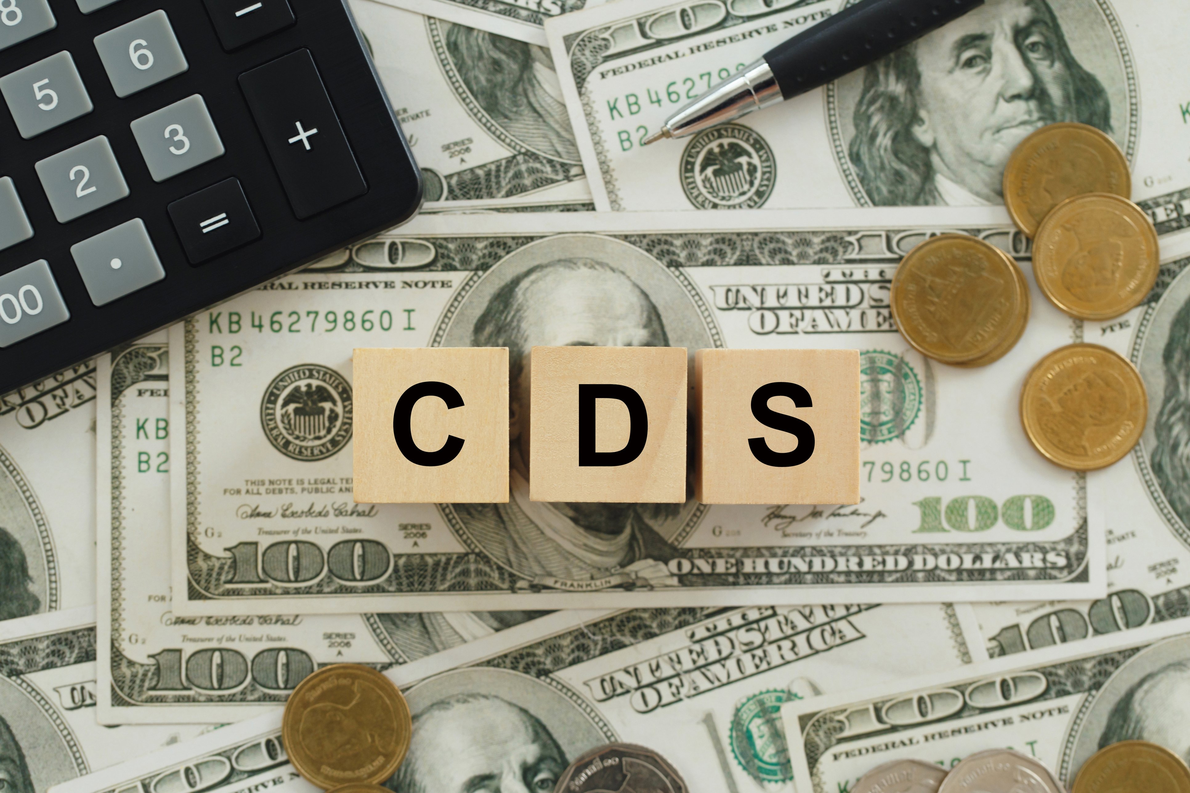 Text CDS written on wooden cubes on top of dollar bills