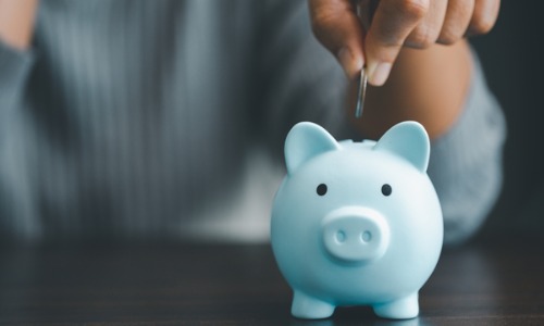 Man putting coin into blue piggy bank 