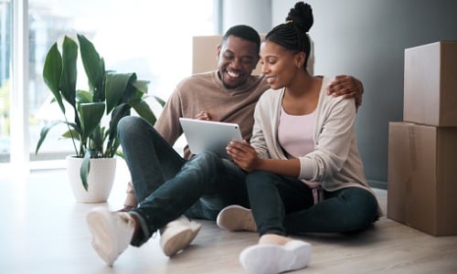 Young couple using tablet while moving into home