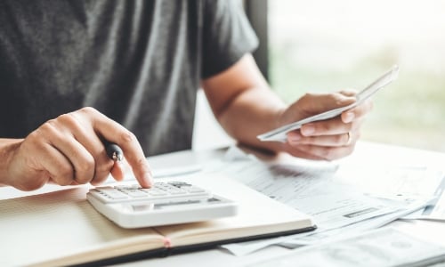 Person adding up bills on a calculator