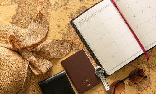 Planner, passport, and a watch ready to be packed for travel