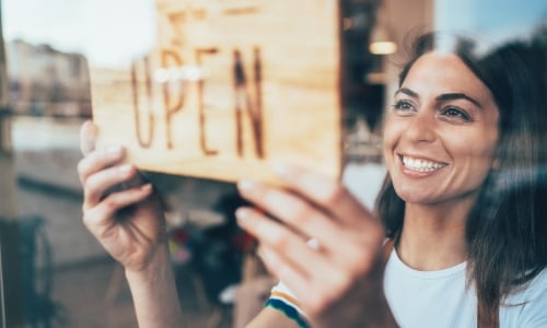 Business owner hanging open sign in window