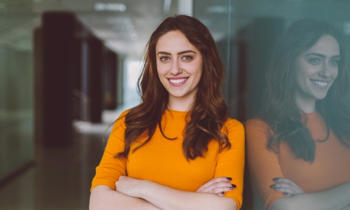 A young woman leaning against a glass wall