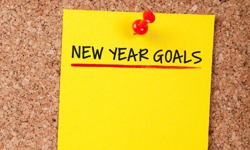 "New Year Goals" written on a bright yellow sticky note
