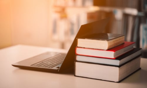 A stack of books next to a laptop