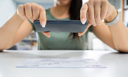 Woman taking a picture of a check with her cell phone