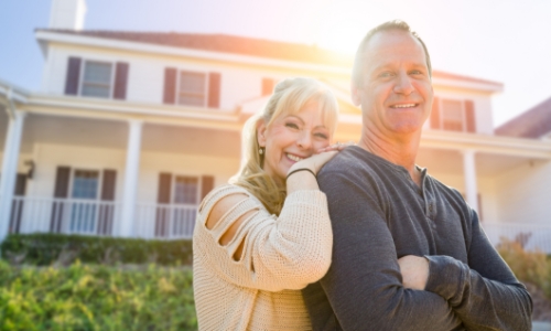 A couple smiling in front of a house