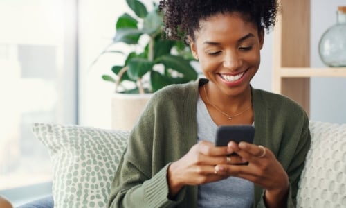 A woman sitting on the couch and using her cell phone