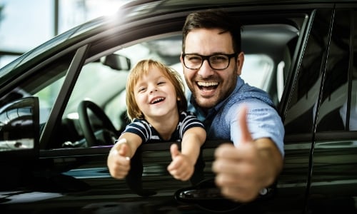 Father and son hanging outside of a car window