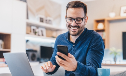 A guy smiling at his cell phone