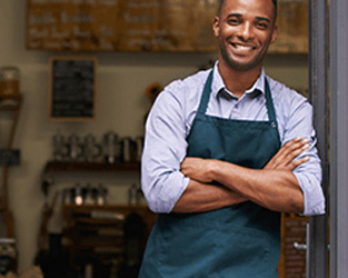 business owner outside his store and wearing an apron