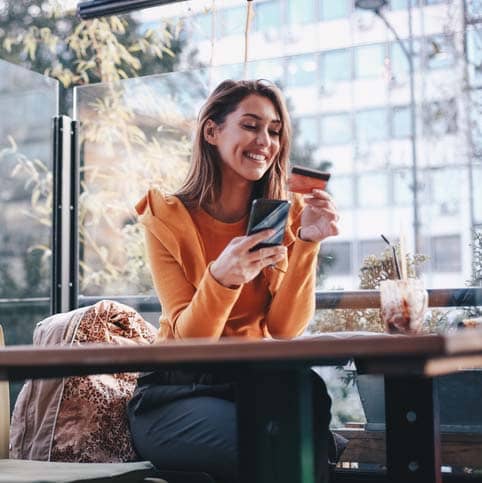 young woman holding a smart phone and credit card