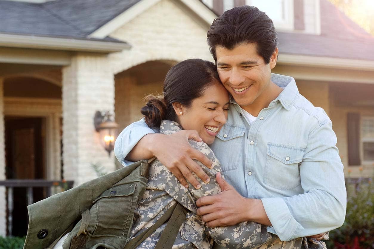 a couple hugging in front of a house
