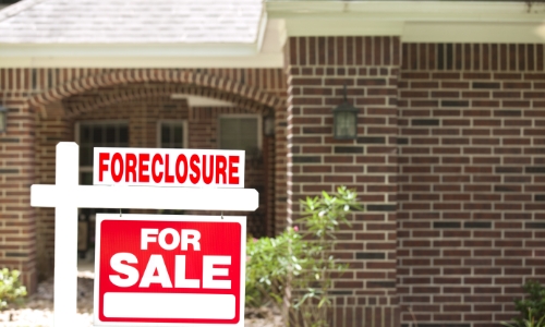 For Sale and foreclosure sign in front of a house
