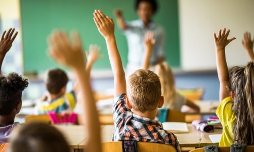 Kids raising their hands in a classroom