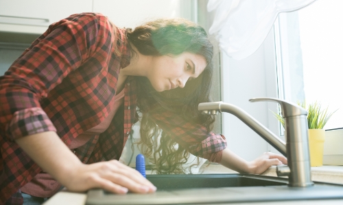 Woman fixing the kitchen faucet