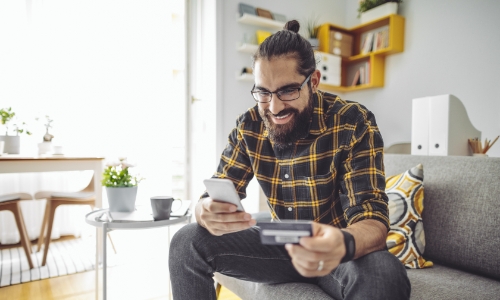 Man using credit card to shop on his cell phone