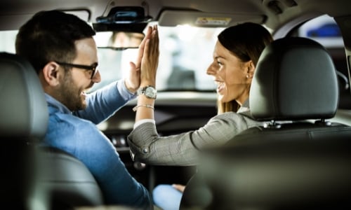 Man and a woman in a car giving a high-five