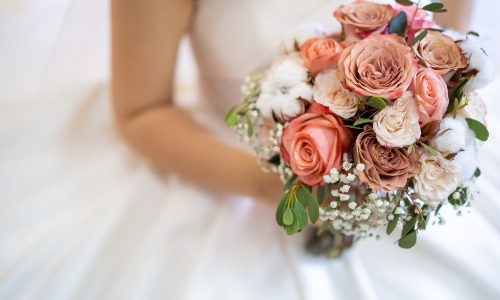 A close up of a bride and her coral flower wedding bouquet