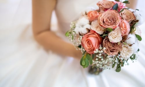 A close up of a bride and her coral flower wedding bouquet