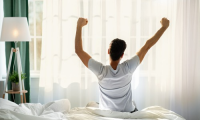 Man stretching in bed after waking up