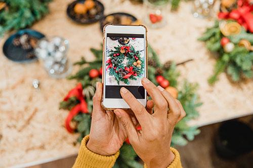 A person taking a photograph of a holiday wreath